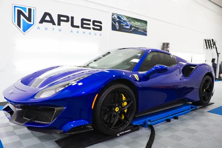 A blue ferrari 488 pista is sitting on a lift in a garage.