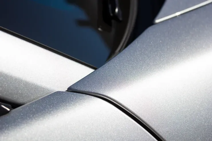 A close up of the side of a silver car with a black trim.