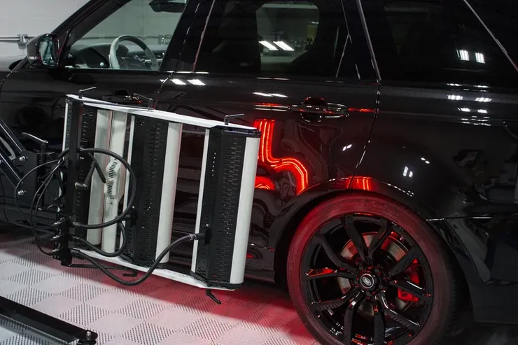 A black car with a ladder attached to the side of it