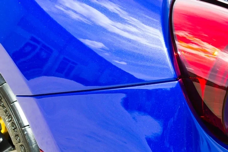 A close up of a blue car with a red tail light