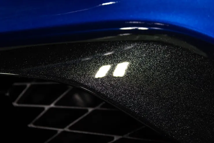 A close up of a blue car with a black grille