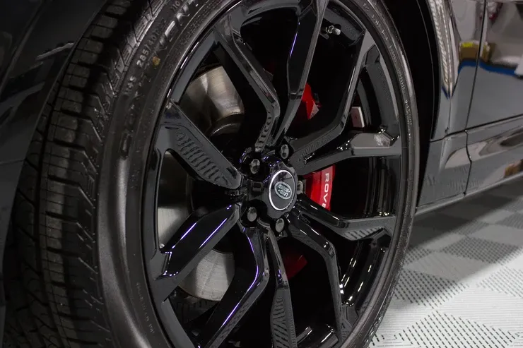 A close up of a black car wheel with red brake calipers.