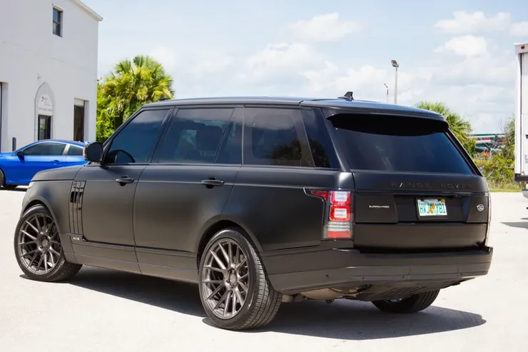 A black range rover is parked in a parking lot.