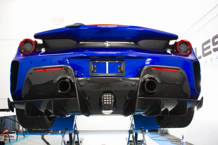 A blue sports car is sitting on a lift in a garage.