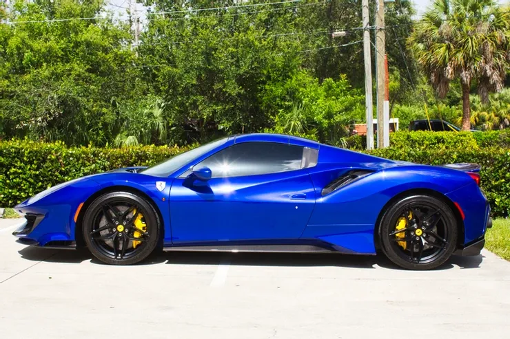 A blue ferrari 488 spider is parked in a parking lot.