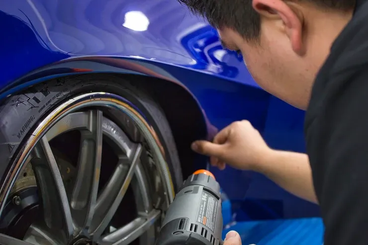 A man is working on a car wheel with a tool.