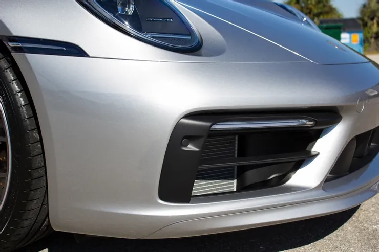 A silver porsche 911 is parked on the side of the road.