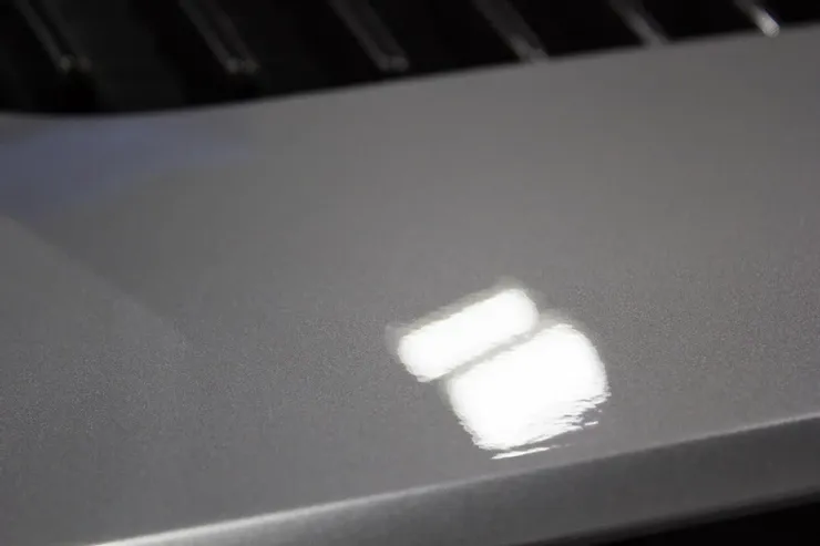 A close up of a silver keyboard with a reflection of a light on it.