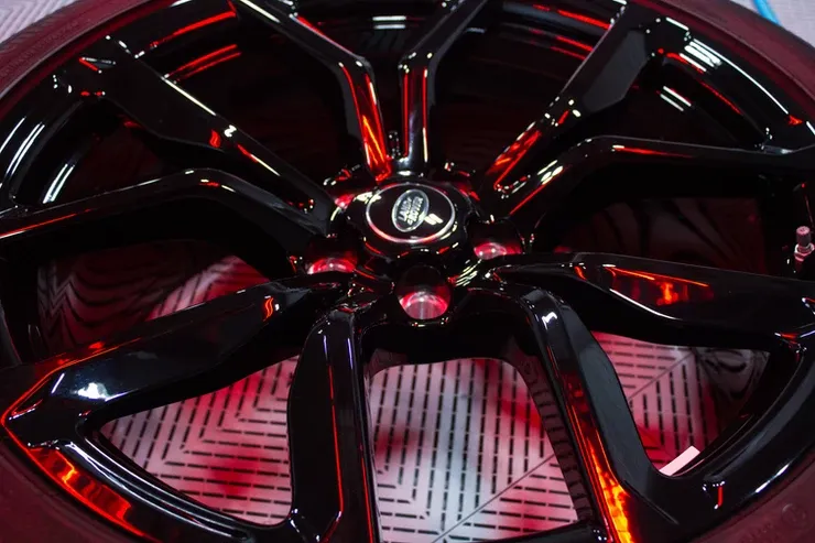 A close up of a black car wheel with red rims