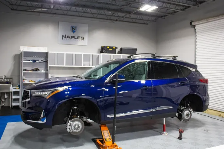 A blue car is sitting on a lift in a garage.
