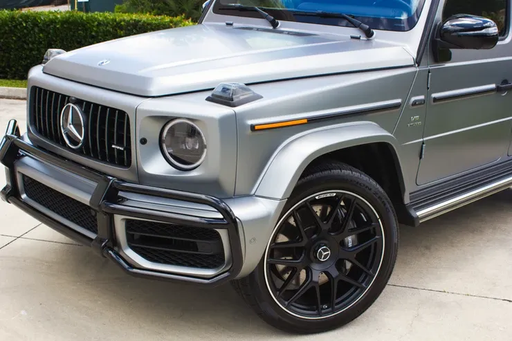 A silver mercedes benz g63 amg is parked in a driveway.