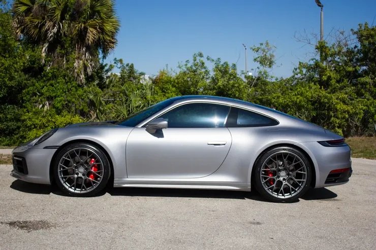 A silver porsche 911 is parked in a parking lot.