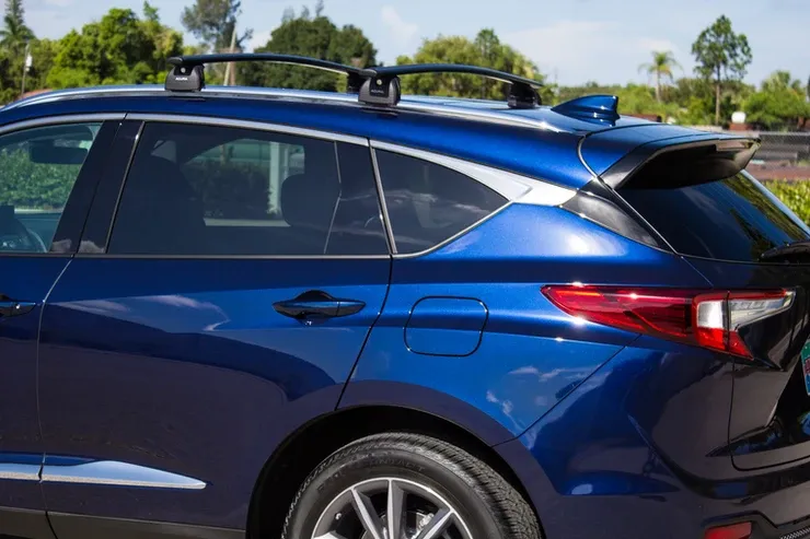 A blue car with a roof rack is parked in a parking lot.