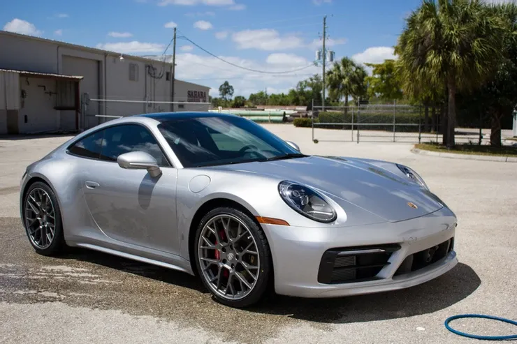 A silver porsche 911 is parked in a parking lot