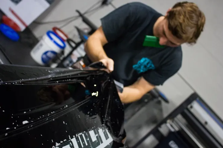 A man is wrapping a car with a sticker that says youth