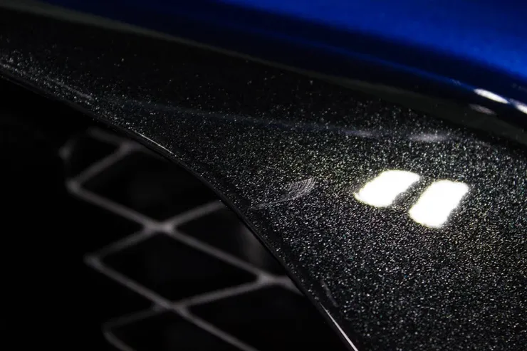 A close up of a blue car with a black fender