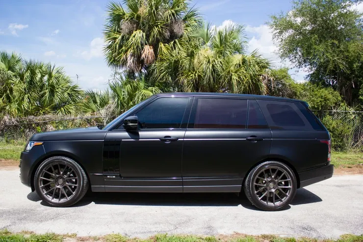 A black range rover is parked on the side of the road.