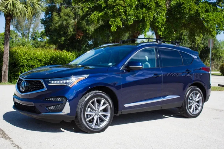A blue acura rx is parked on the side of the road.