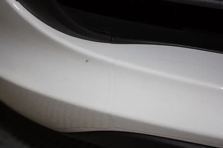 A close up of a white car bumper with a black trim
