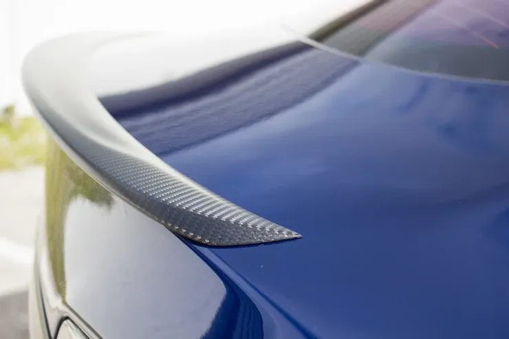 A blue car with a black spoiler on the back