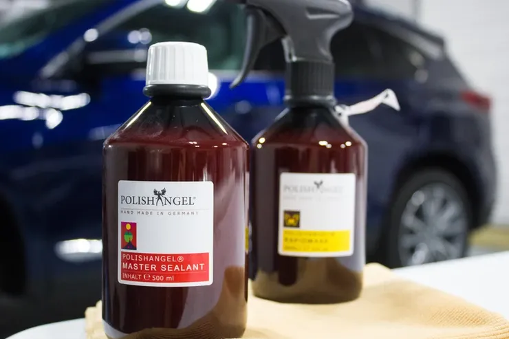 Two bottles of polishangee sit on a table in front of a car