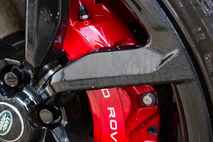 A close up of a red brake caliper on a car wheel