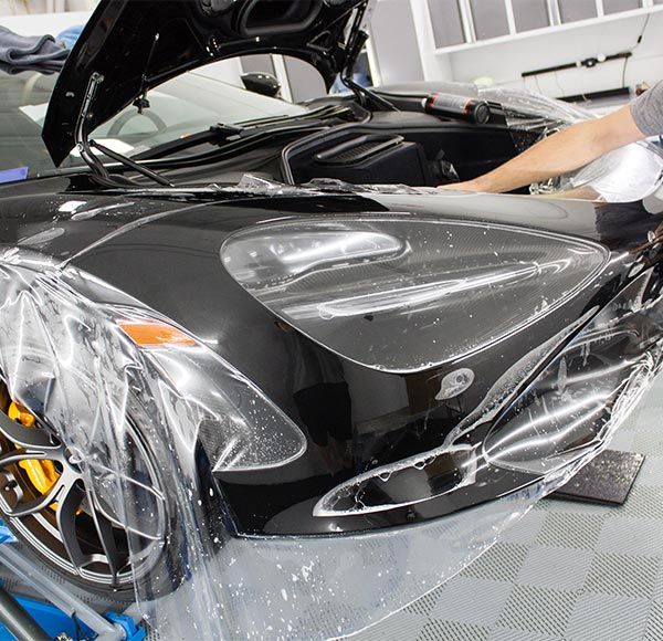 A black car is wrapped in clear plastic
