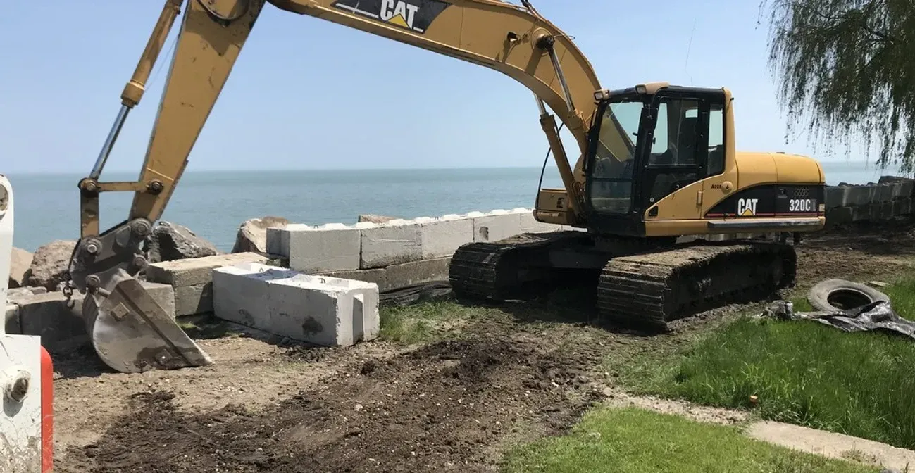 A large excavator is working on a construction site next to a body of water.