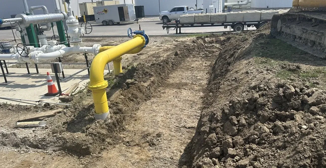 A yellow pipe is sitting in the middle of a dirt field.