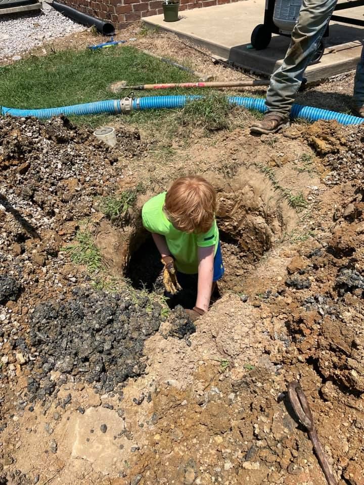 A young boy is digging a hole in the dirt.