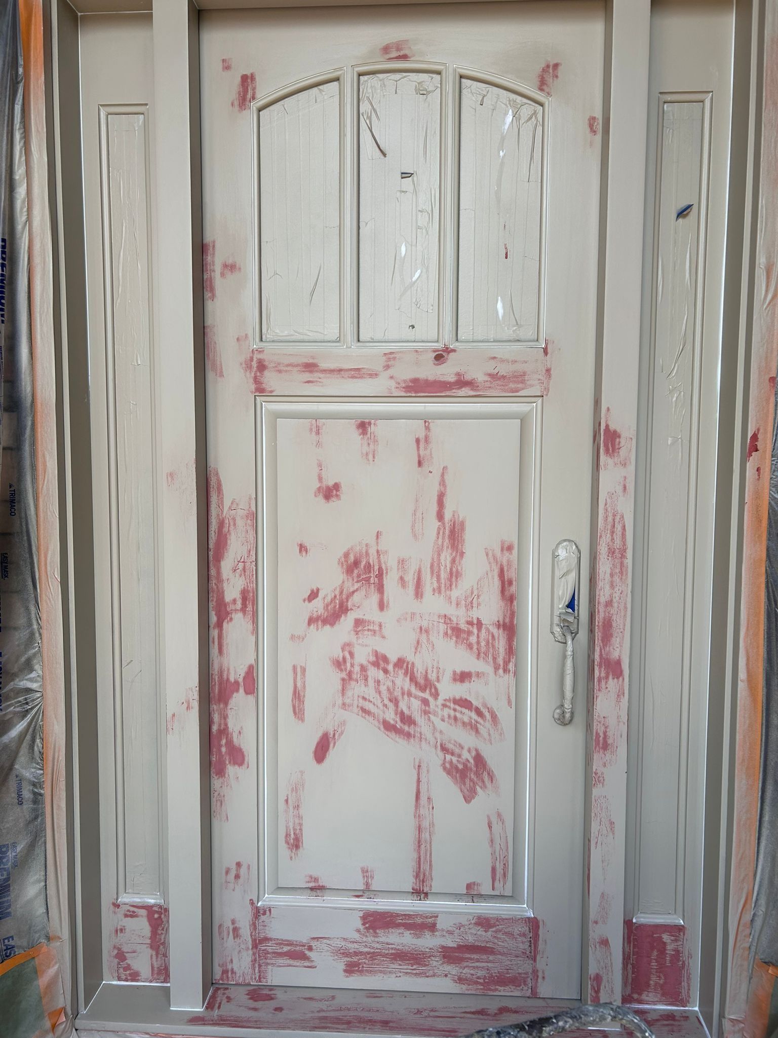 Cream-colored exterior door with peeling paint. Door has glass panes at the top, and silver hardware.