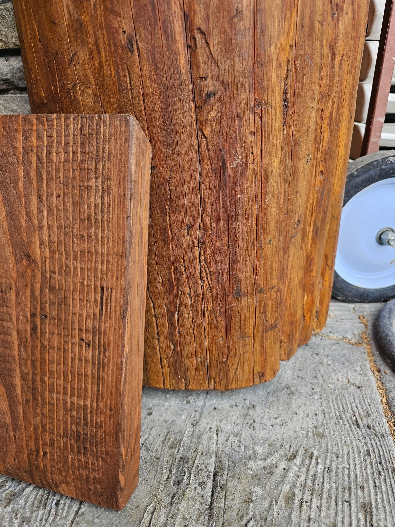 Two weathered wood pieces, one rectangular and one cylindrical, on a concrete surface.
