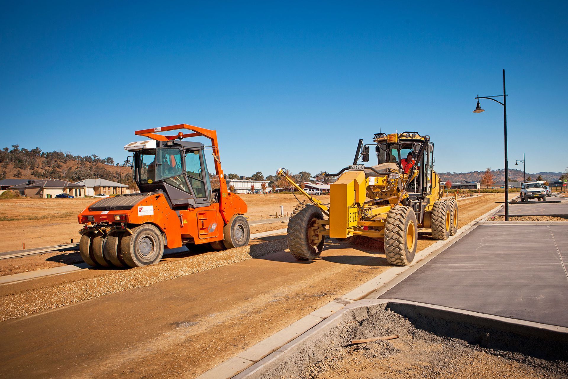 Two construction vehicles are working on a road.