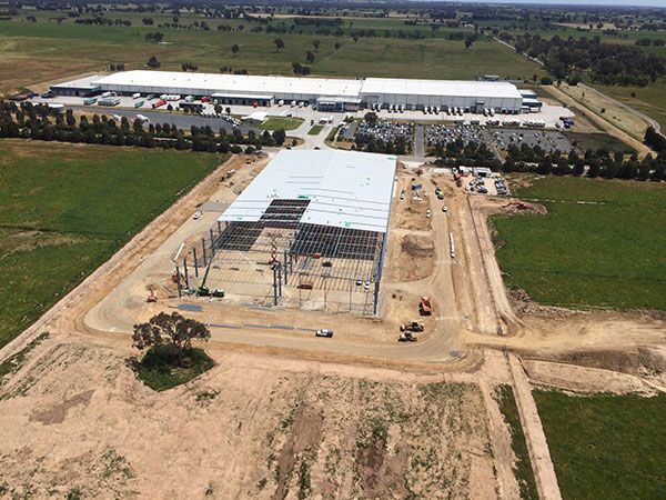 An aerial view of a large building under construction in the middle of a field.