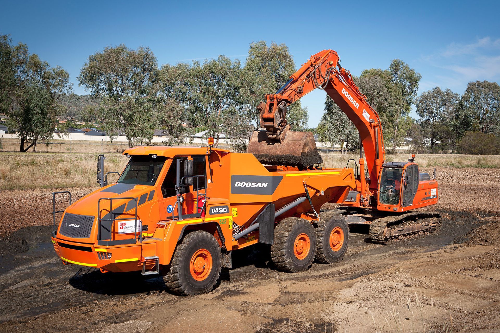 A dump truck is being loaded with dirt by an excavator.