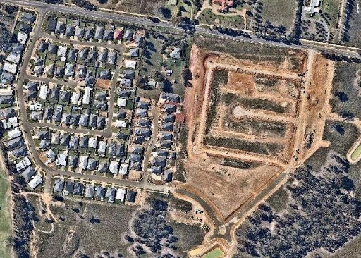 An aerial view of a residential area with a large dirt area in the middle.