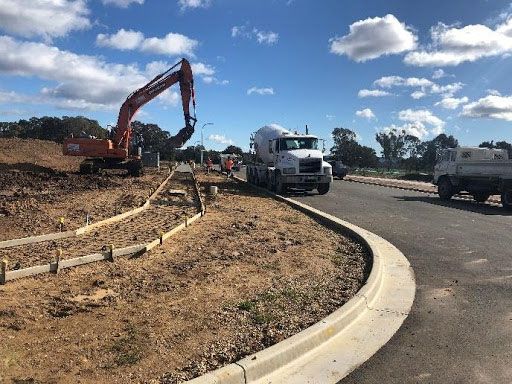 A truck is driving down a road next to a construction site.