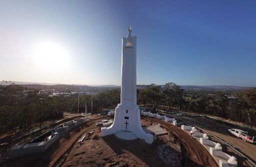 An aerial view of a large white statue on top of a hill.