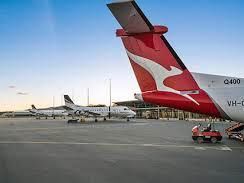 A red and white airplane is parked on the tarmac at an airport.