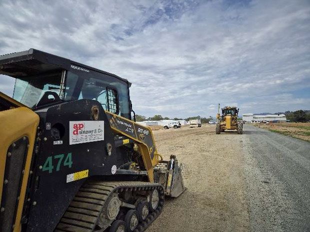 Two bulldozers are parked on the side of a dirt road.