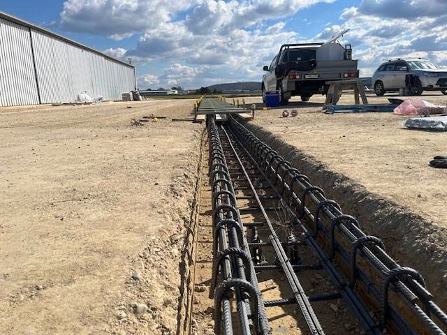 A construction site with a lot of metal bars in the dirt.