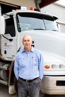 A man is standing in front of a large white truck.