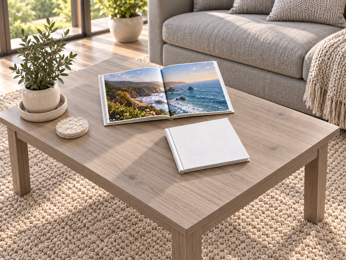 White linen photo books on a rectangular ash-gray table beside a gray sofa