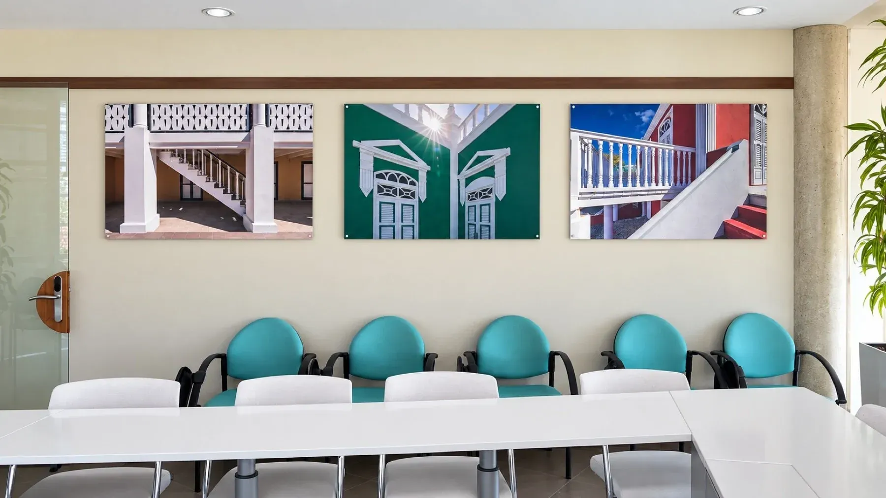 Three architectural metal prints above teal chairs in a meeting room
