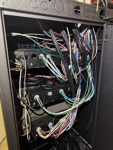 Open server rack with tangled multicolored network cables and hardware equipment