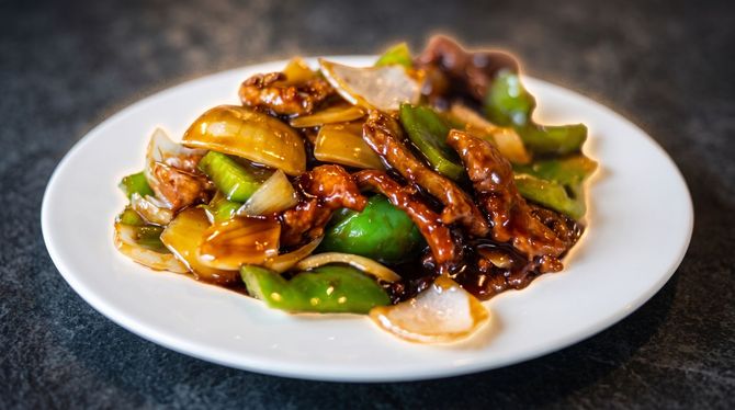 Plate of stir-fried vegetables and meat in glossy brown sauce on a white dish