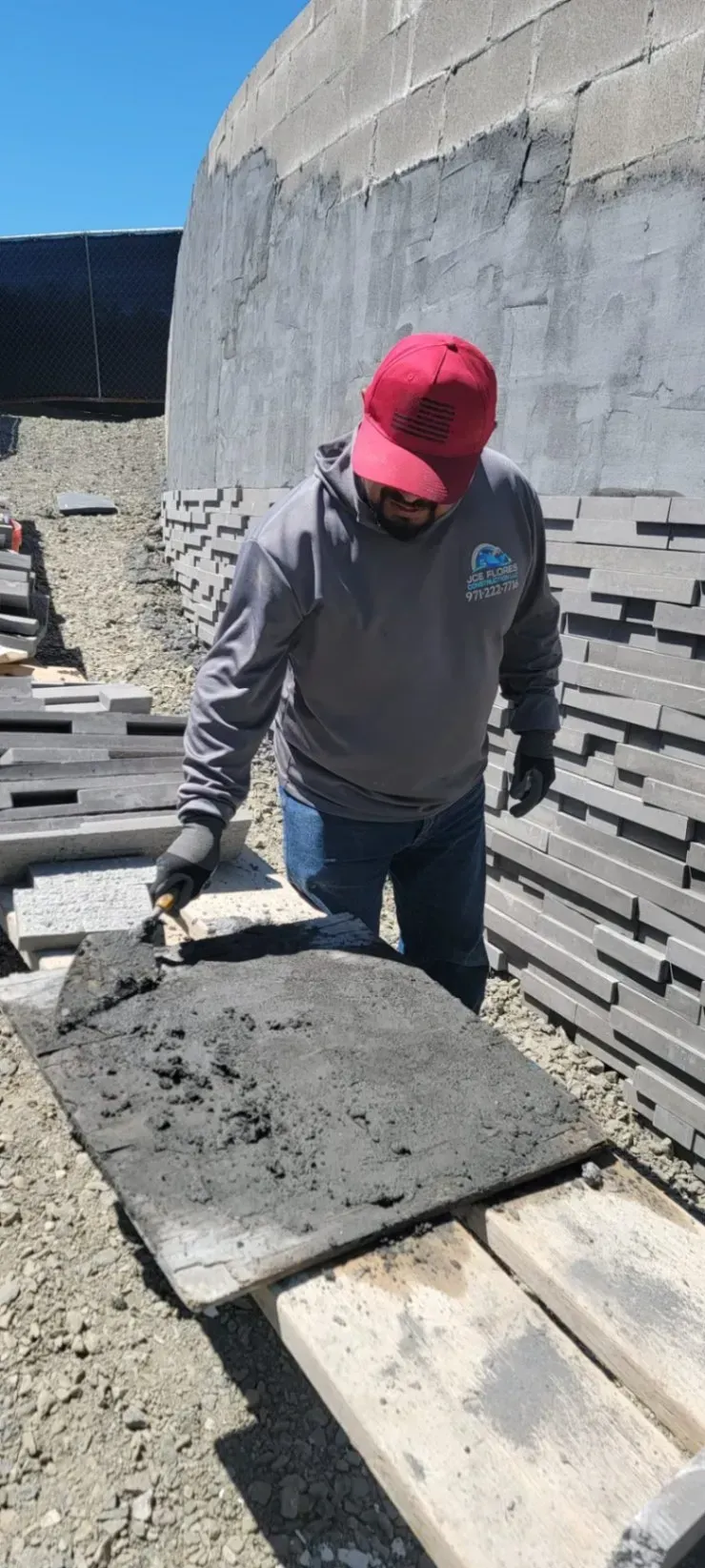 Worker in red cap inspecting concrete slab at a construction site.