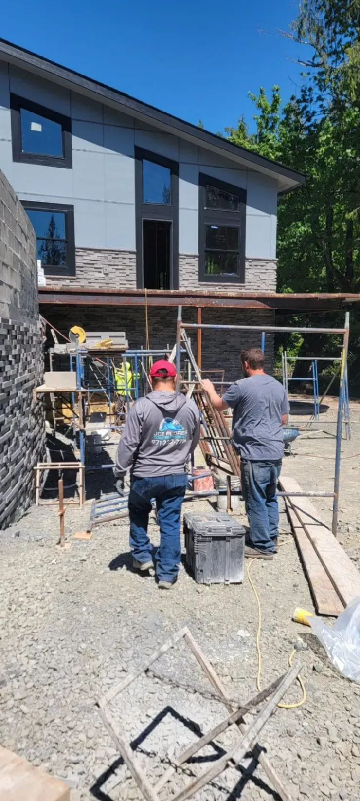 Workers on scaffolding installing a building exterior on a sunny construction site