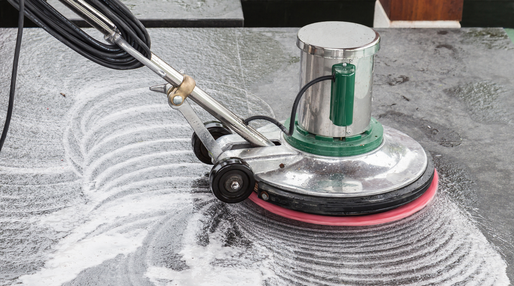 A person is using a machine to clean a tile floor.