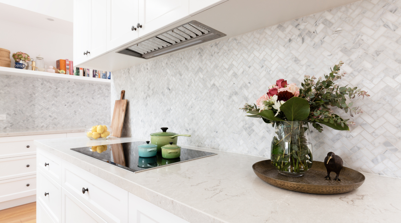 There is a vase of flowers on the counter in the kitchen.